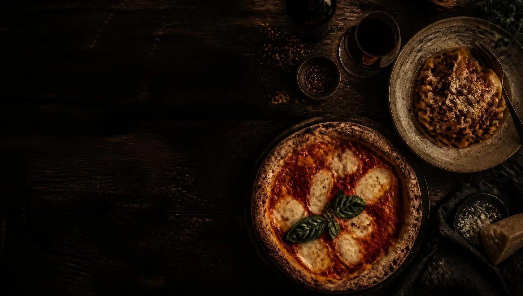 Pizza and pasta on a dark rustic table